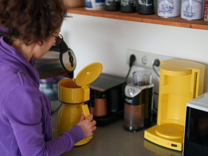 Frau füllt gekochten Filterkaffee in der Küche in eine Thermoskanne