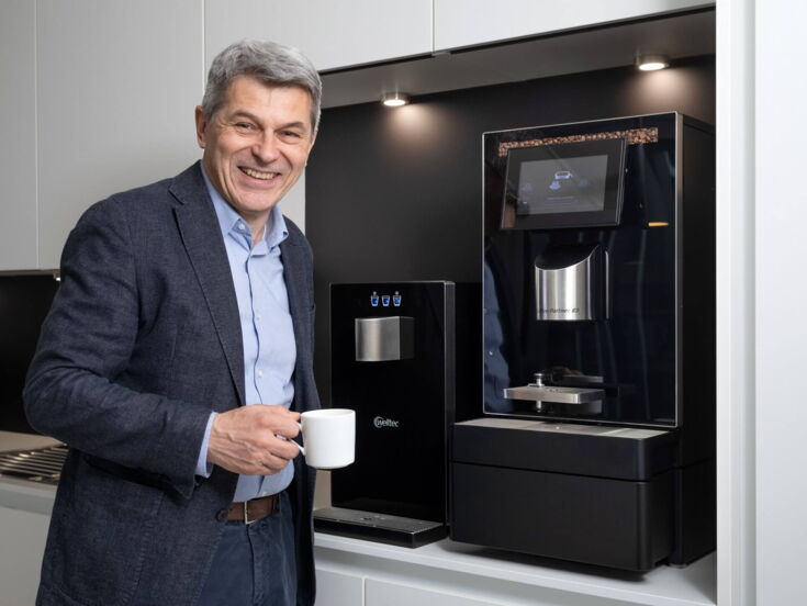 Volker Breid genießt seinen Kaffee vor dem Kaffeevollautomaten und Wasserspender von Kaffee Partner